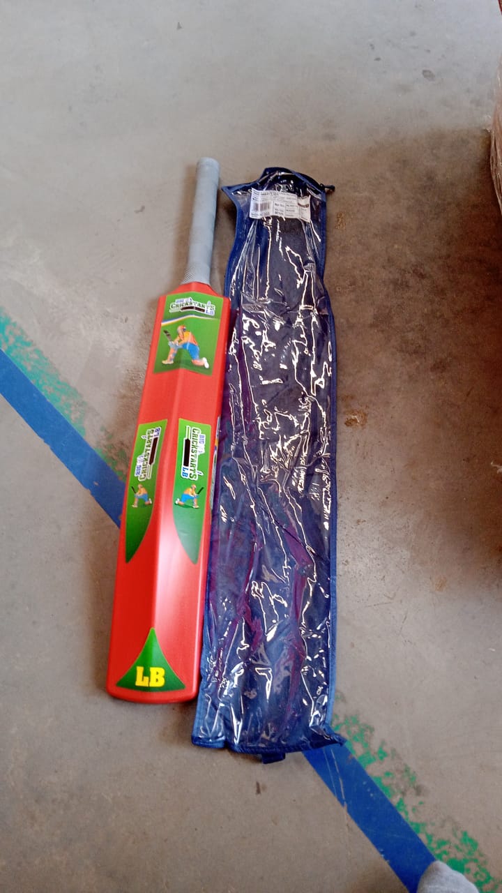A child swinging a plastic cricket bat, enjoying outdoor play.