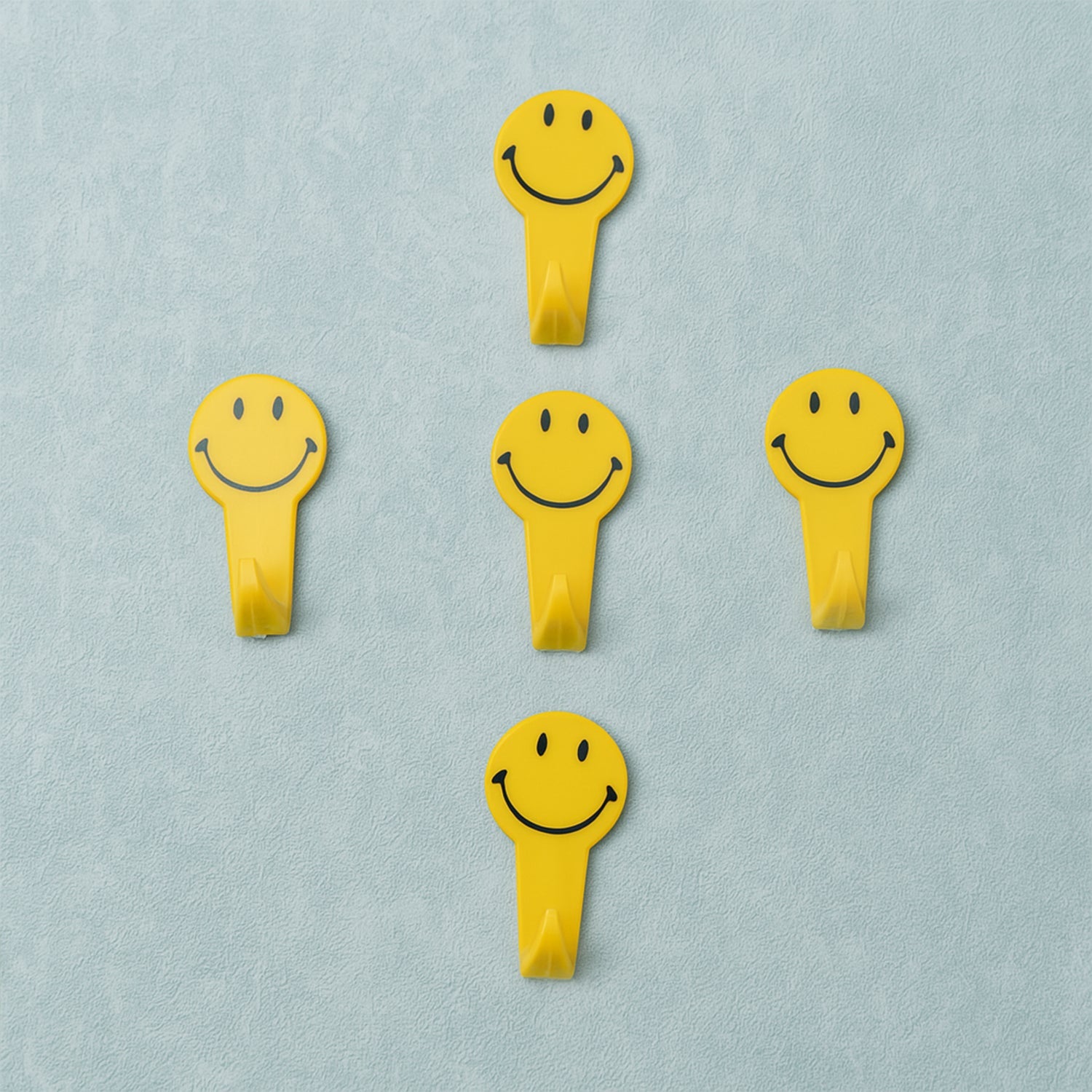 A set of five white self adhesive hooks displayed on a clean surface.