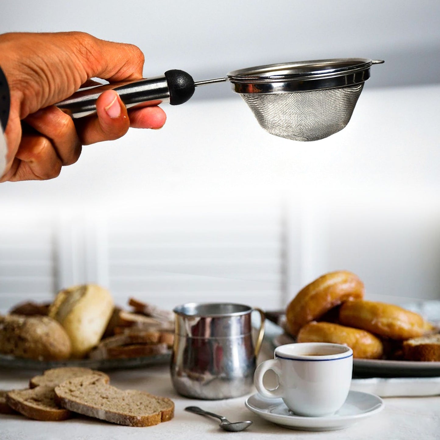 Hand holding a stainless steel strainer, actively filtering soup.