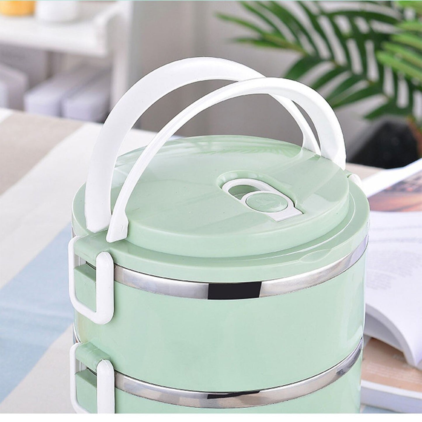 Stainless steel lunch box with three separate compartments for diverse meals.
