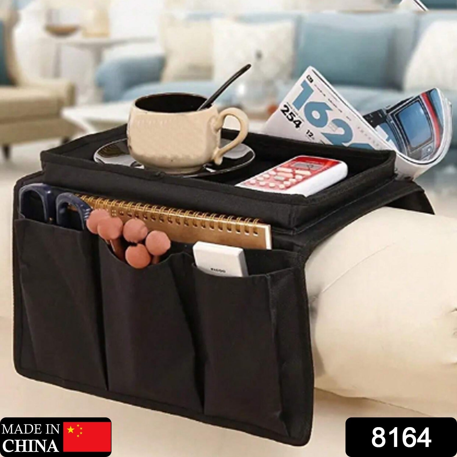 Sofa armrest organizer in black, holding magazines, remotes, and a phone.