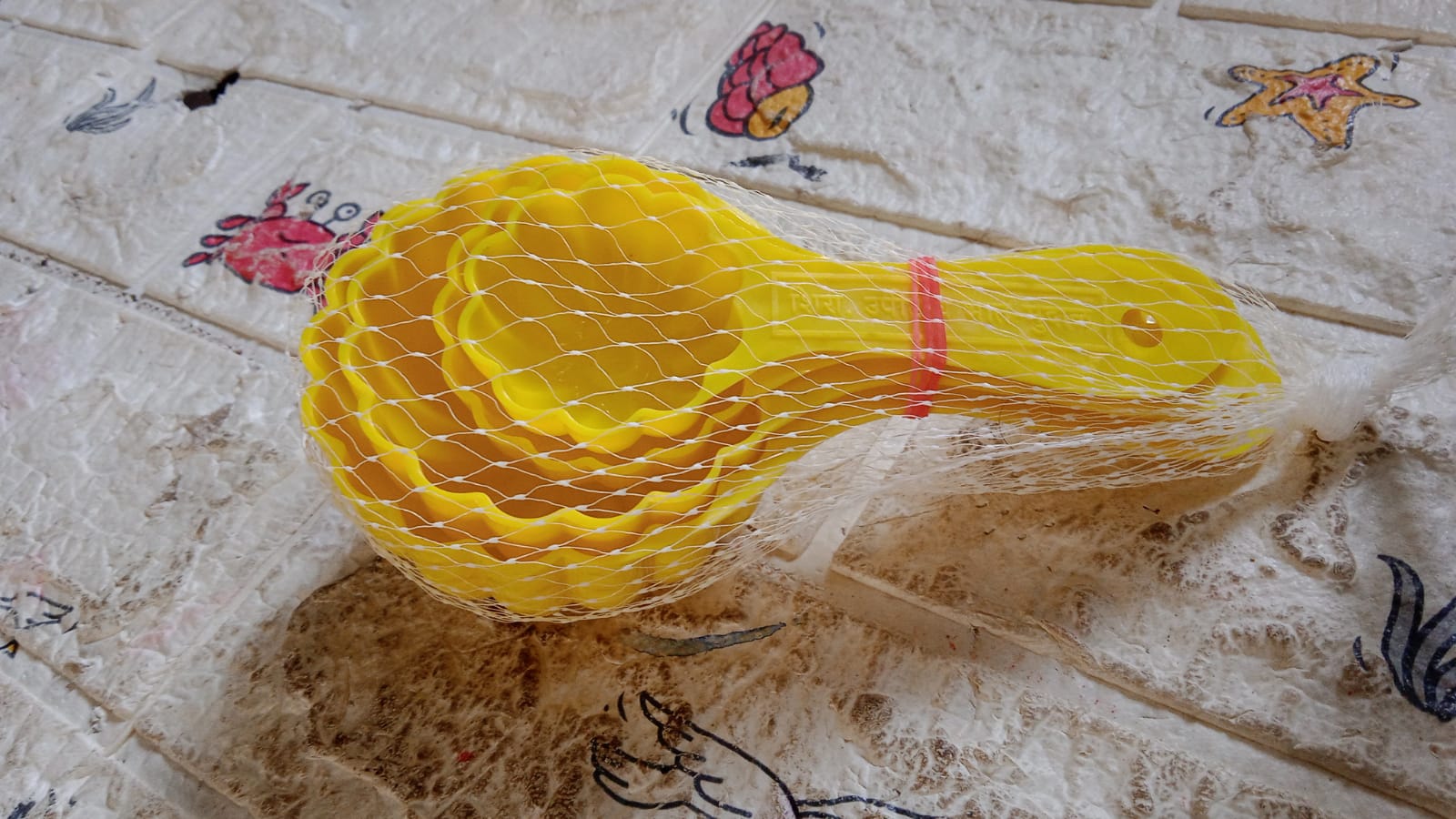 A perfectly shaped ladoo sits next to the plastic mould spoon used to create it.