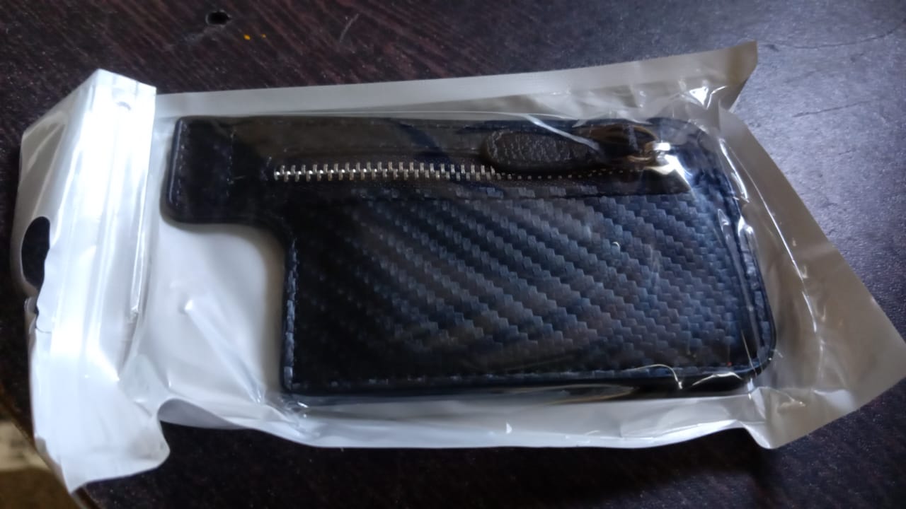A person demonstrating how to easily attach the black adhesive phone card holder to a smartphone.