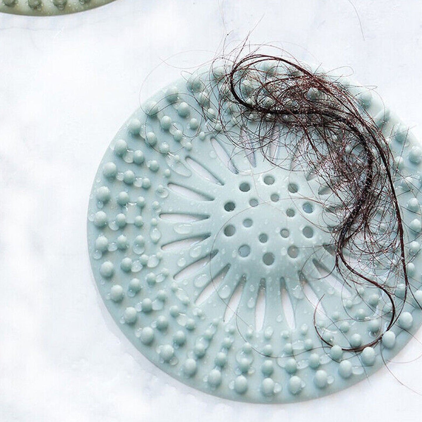 Durable silicone drain cover protecting a shower drain from clogs caused by hair.