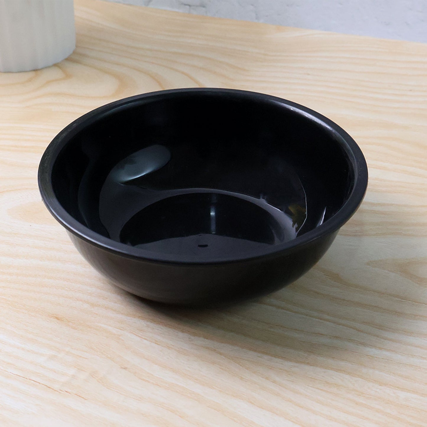 Black round plastic serving bowl on white background