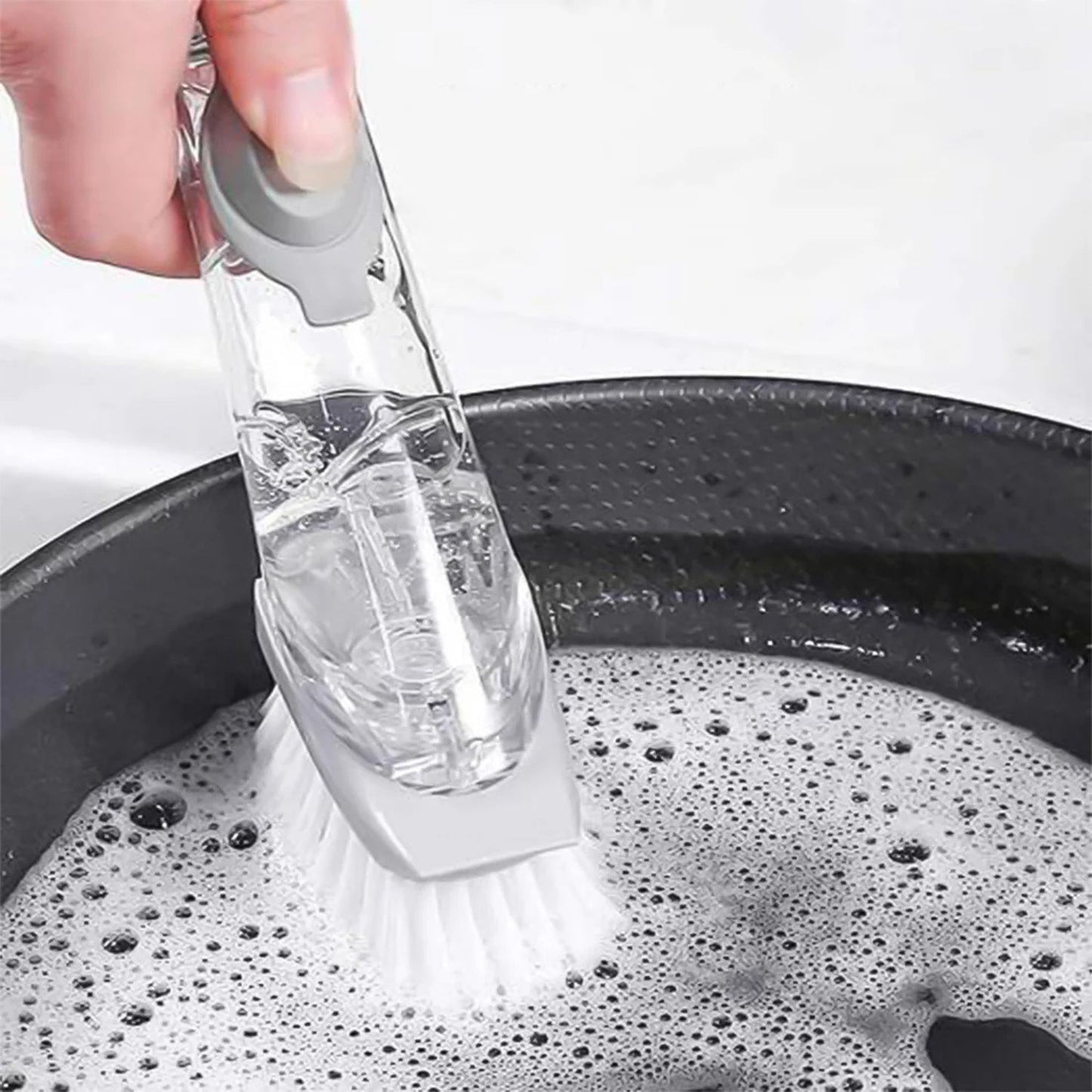 Hand demonstrating the controlled soap dispensing action of the dish brush