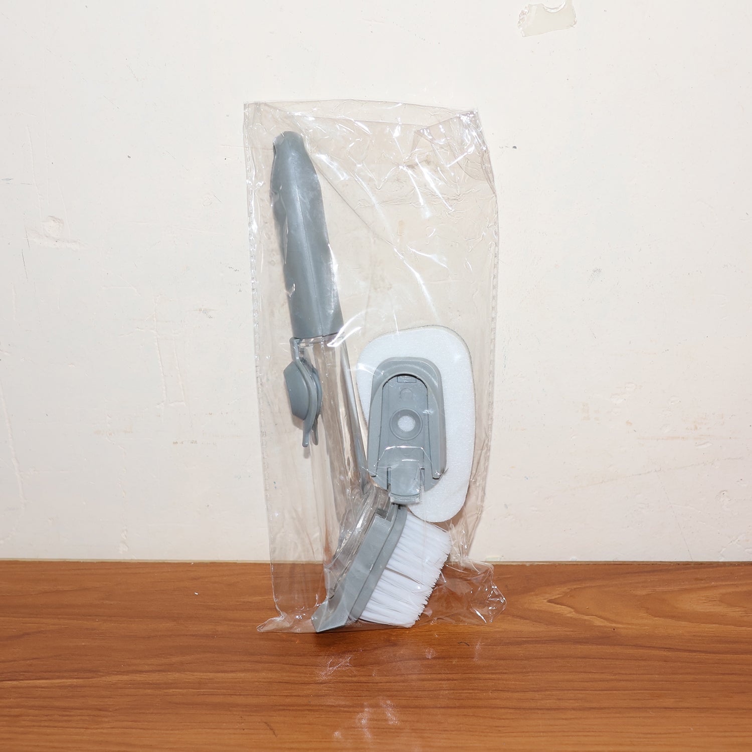 Soap-dispensing dish brush in action, cleaning food residue from a plate