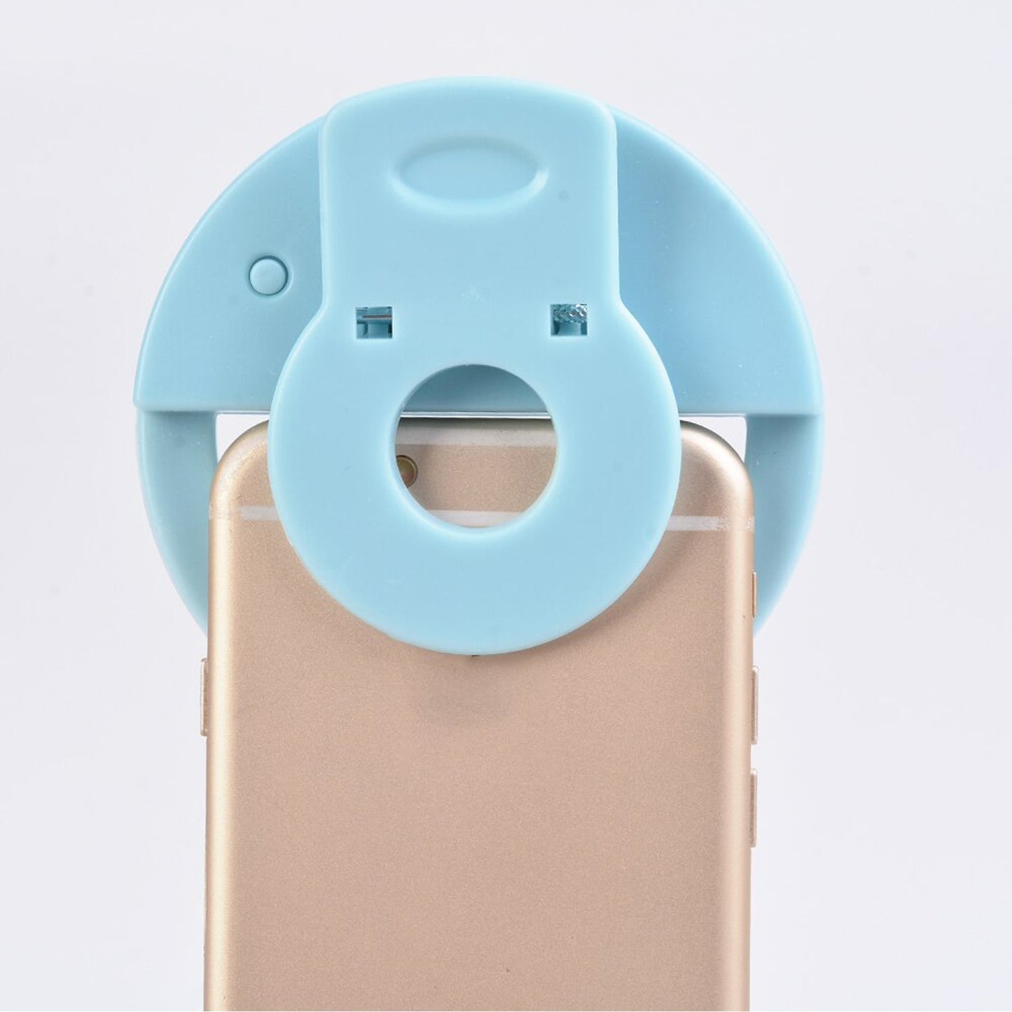 LED selfie ring light held by hand, shining bright light on a smartphone.