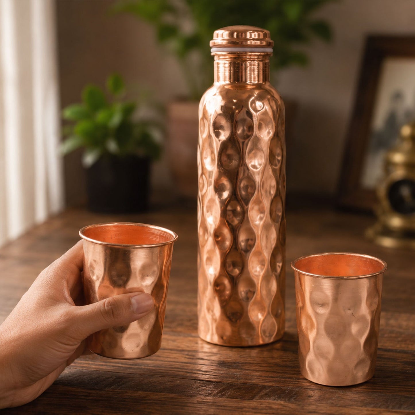 Diamond cut copper water bottle set with two matching glasses on a light background.