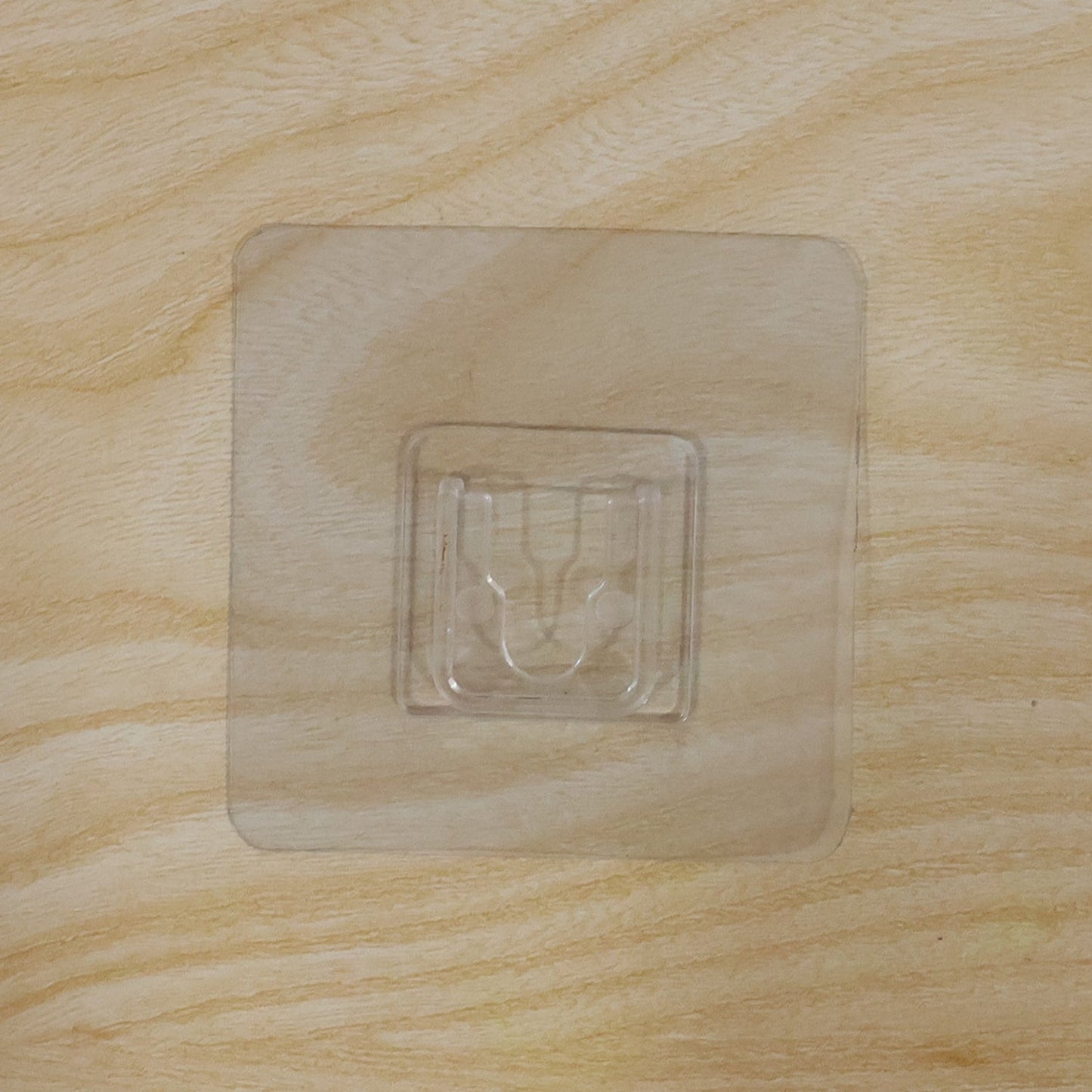 Pack of multiple transparent self-adhesive wall hooks.