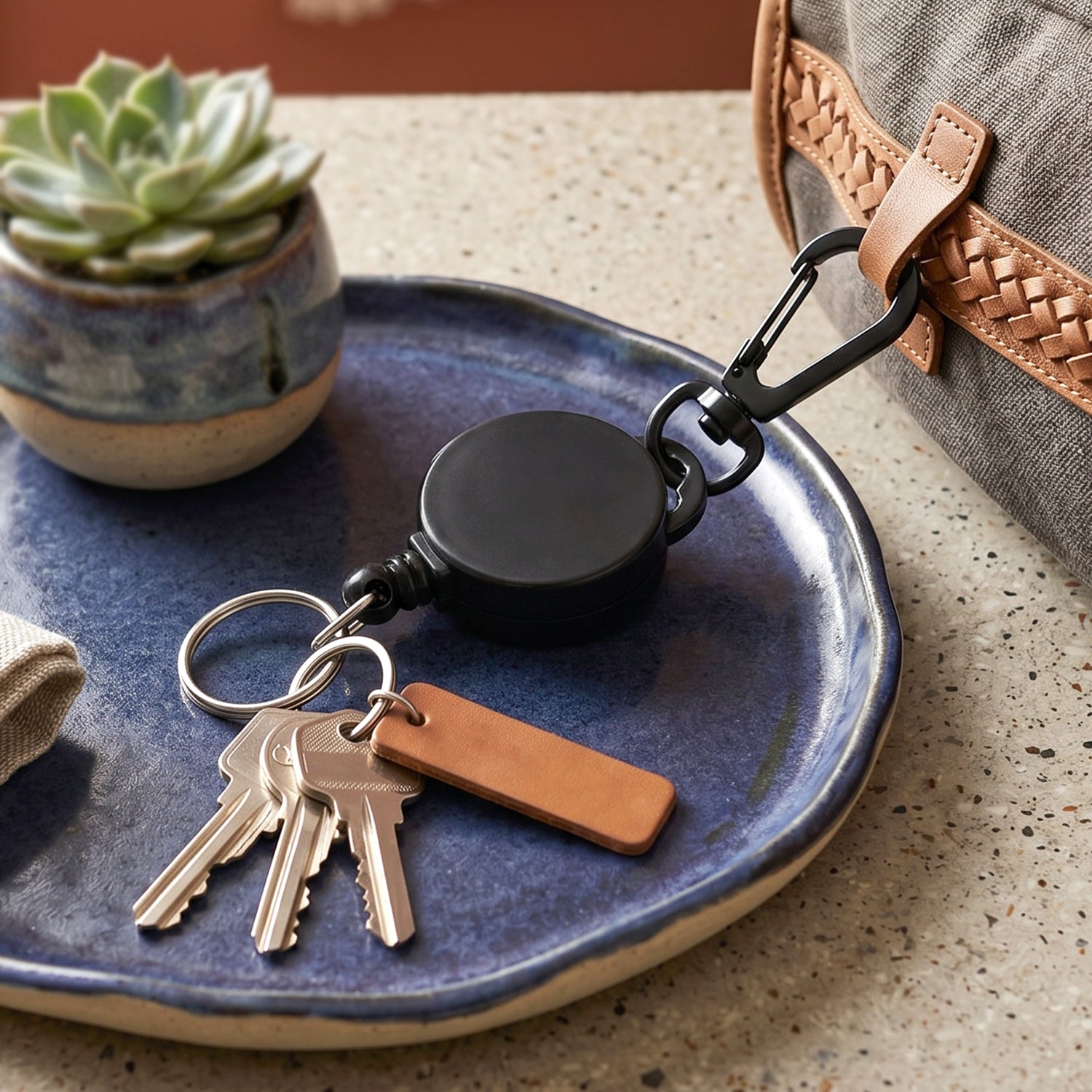 Durable retractable keychain hanging from a bag strap for easy access.