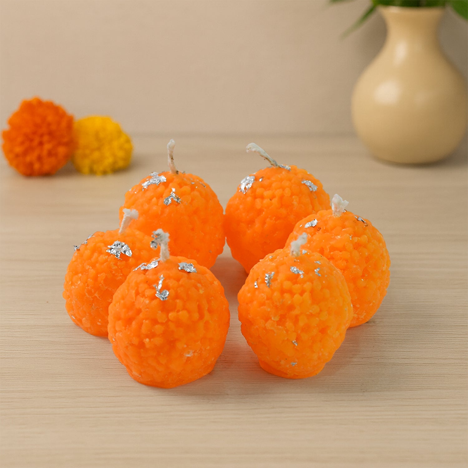 Close-up of laddu shaped wax candle with intricate silver leaf design