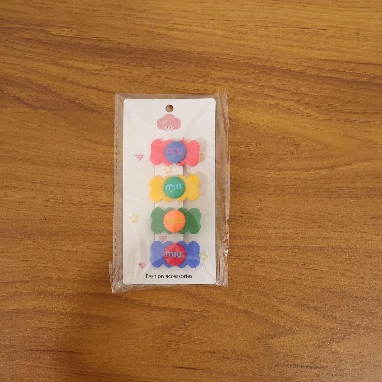 Hand holding a colorful candy hair clip showing its size and vibrant design