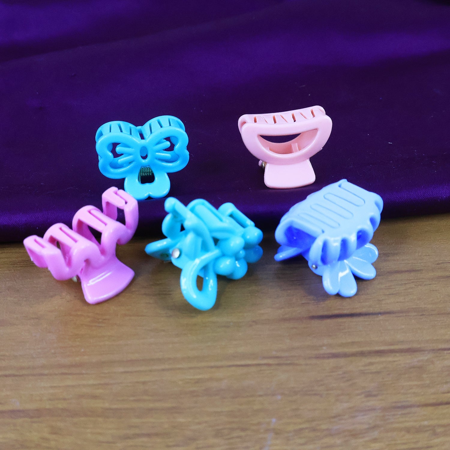 Mini hair claw clips in mixed vibrant colours scattered on a surface.