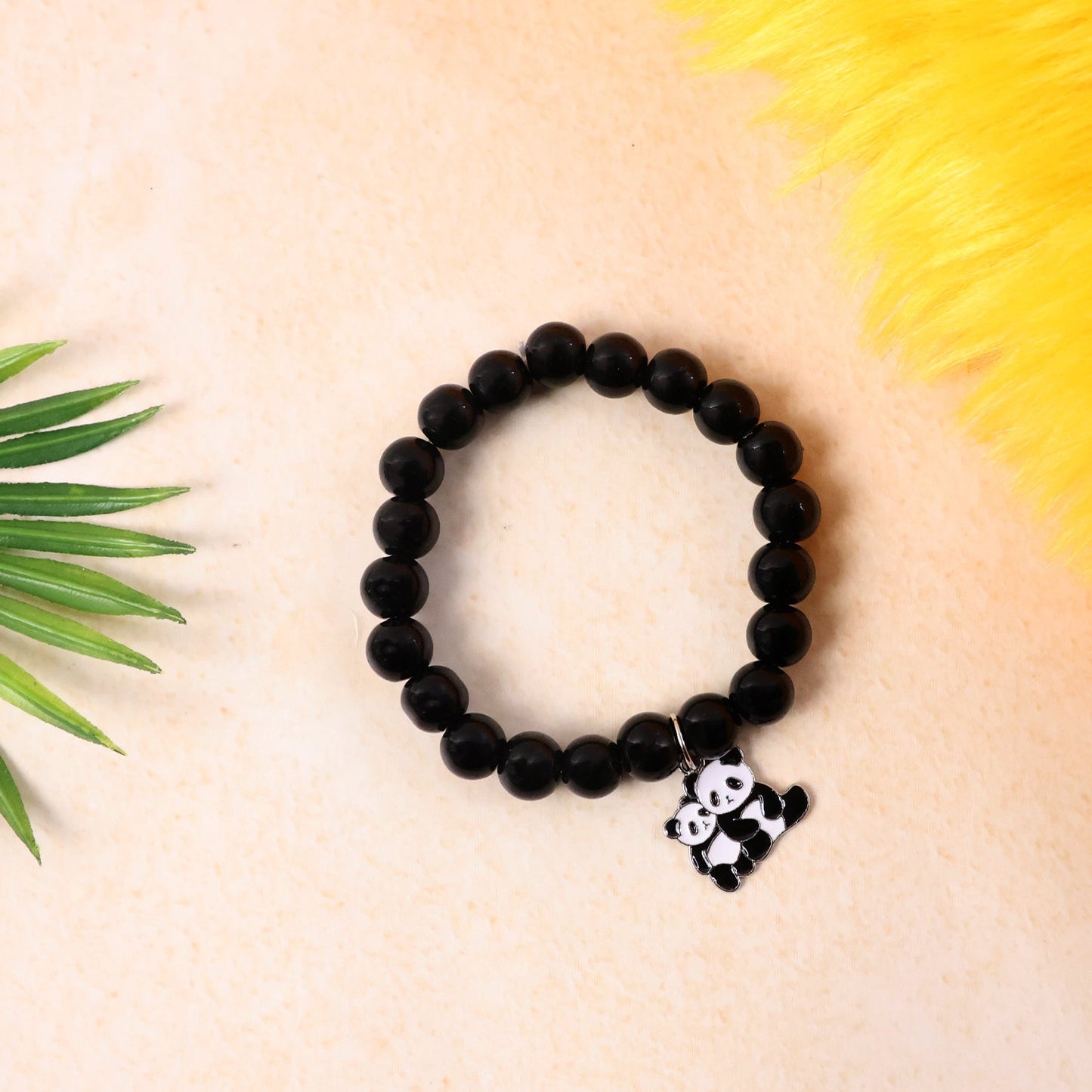 Black beaded bracelet featuring a panda charm worn on wrist.