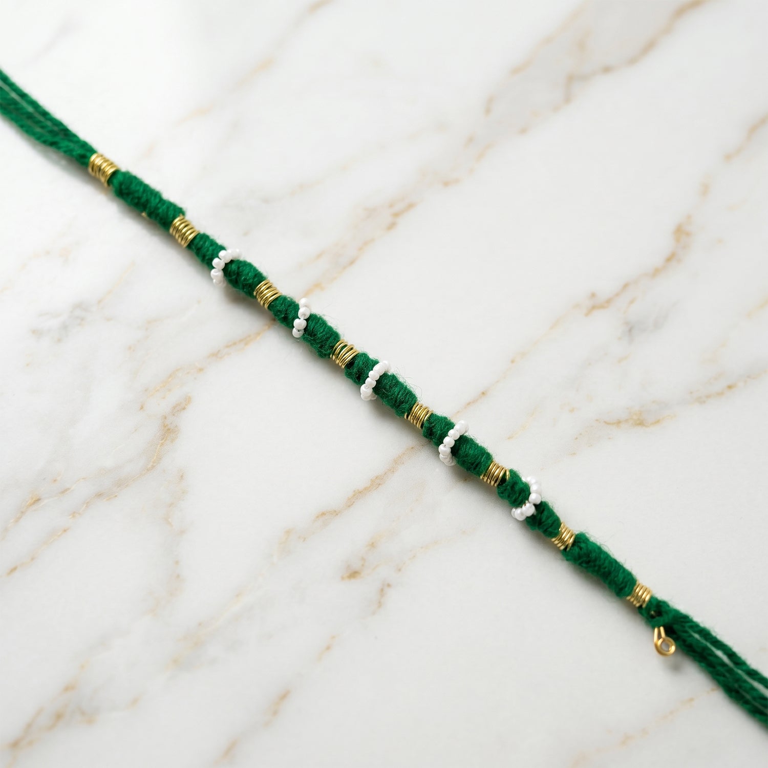 Traditional green rakhi showcasing pearl and golden bead accents