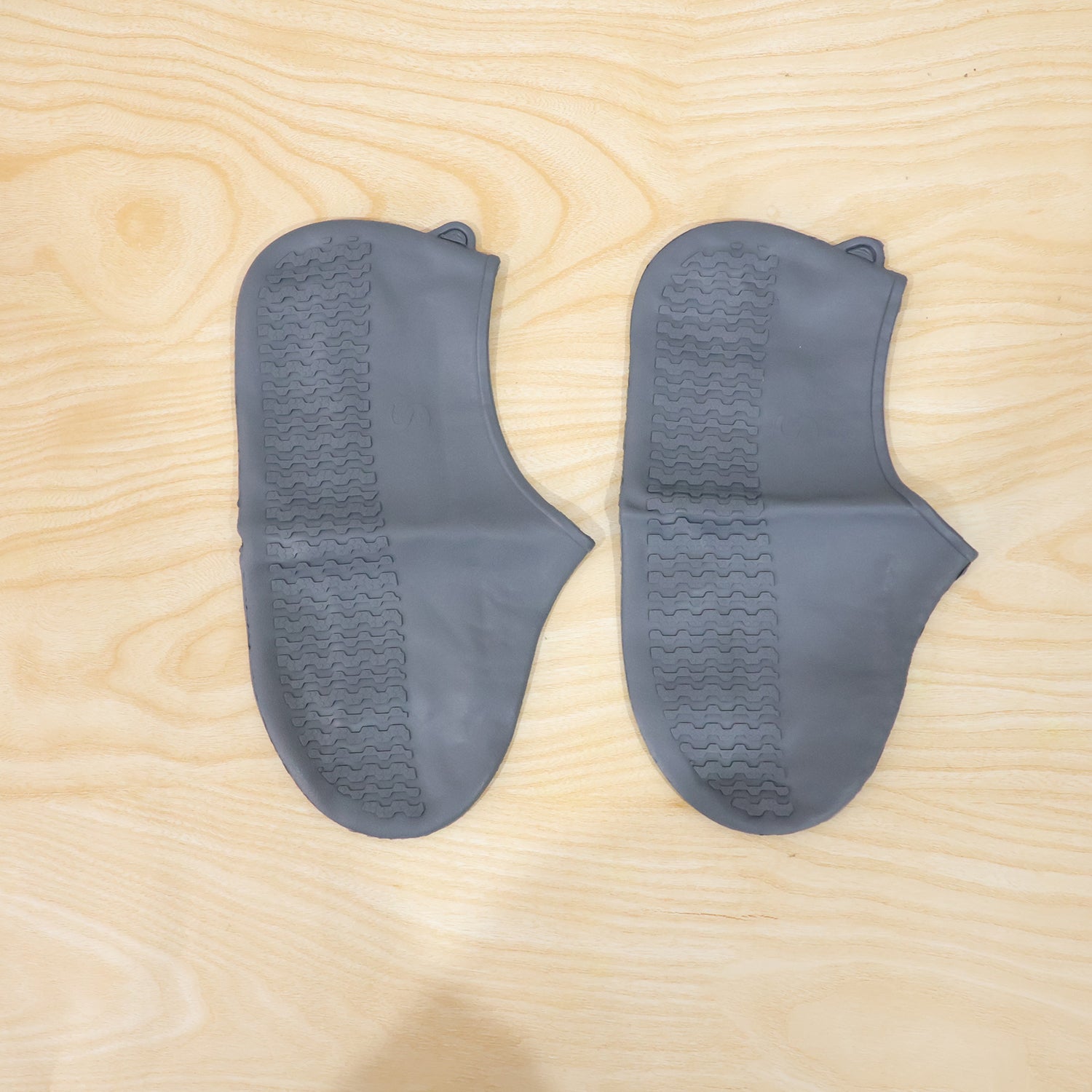 Waterproof silicone shoe covers being worn by a person walking through a muddy park.