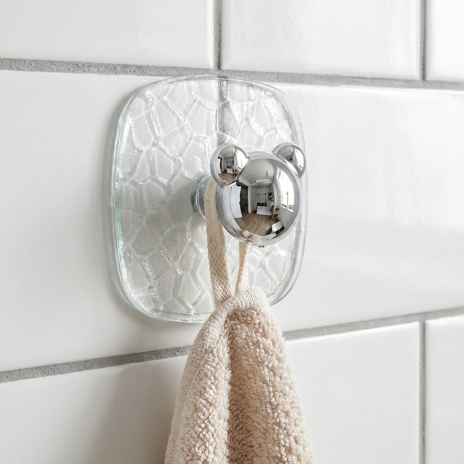 Close-up of clear plastic adhesive wall hook holding a kitchen towel securely.