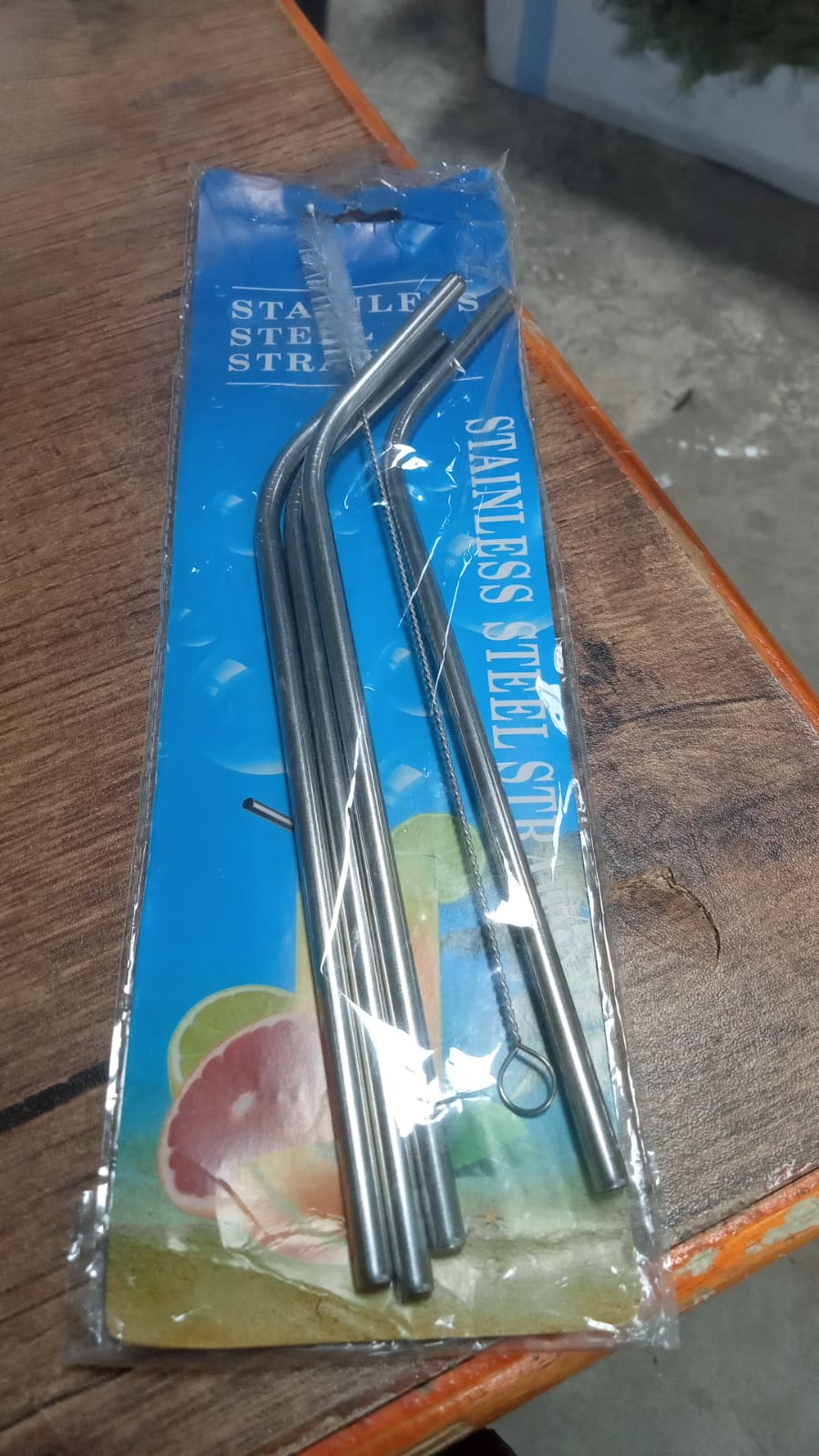 Hand holding a glass with an eco-friendly bent stainless steel straw, promoting sustainable living in India.
