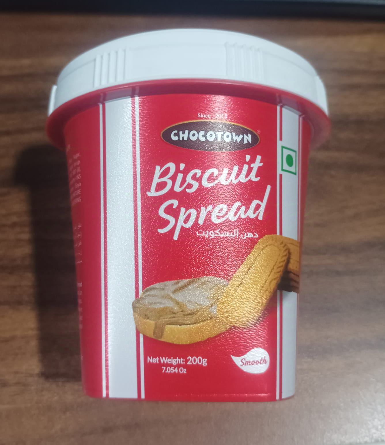 A spoon dipped into a jar of Chocotown Caramelised Biscuit Spread, demonstrating its smooth consistency.