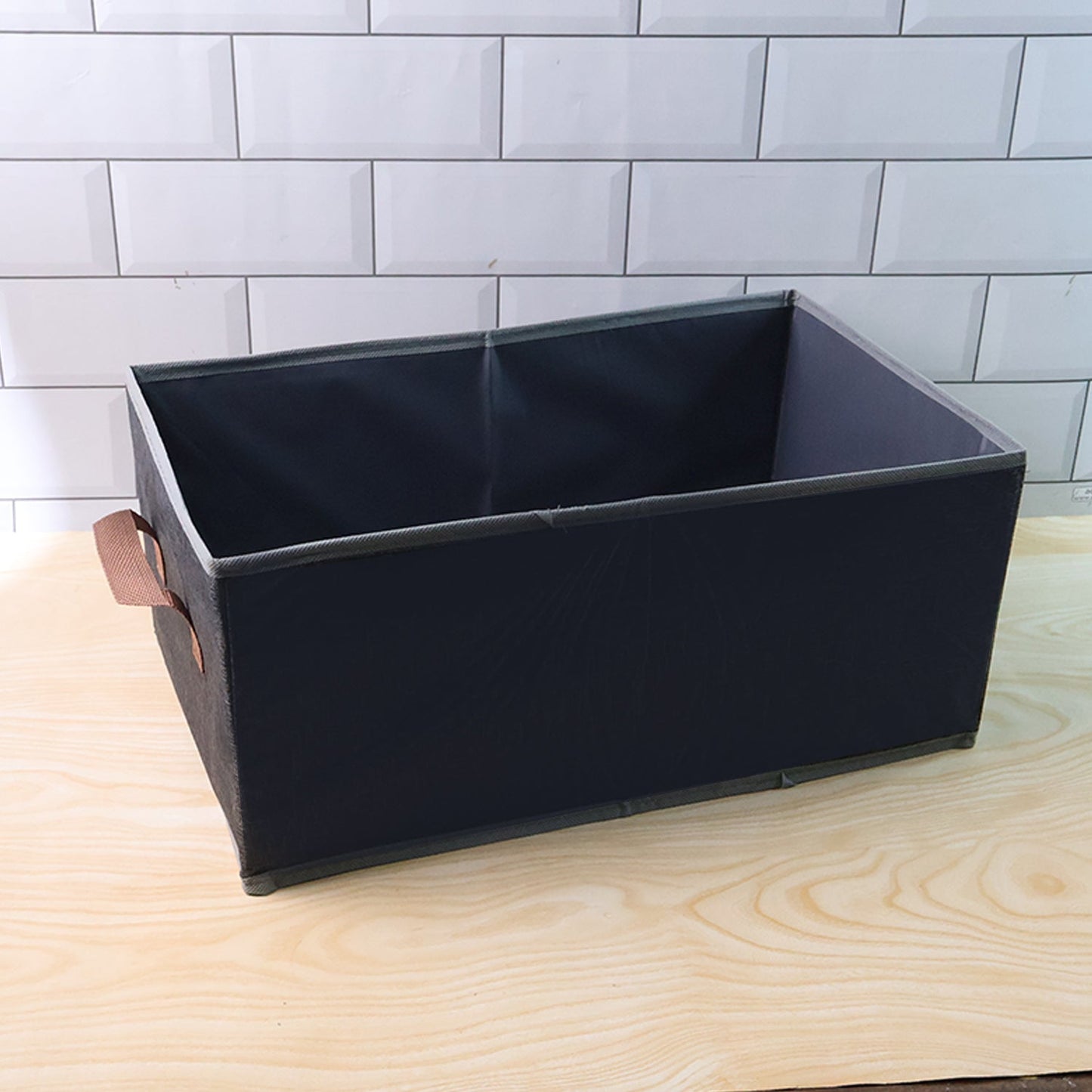 Foldable rectangular organizer bin shown neatly holding household items