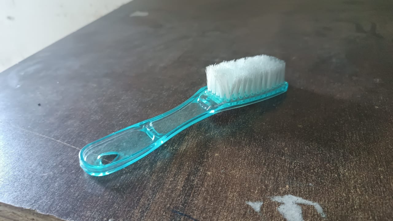 Plastic scrubbing brush featuring an ergonomic handle design.