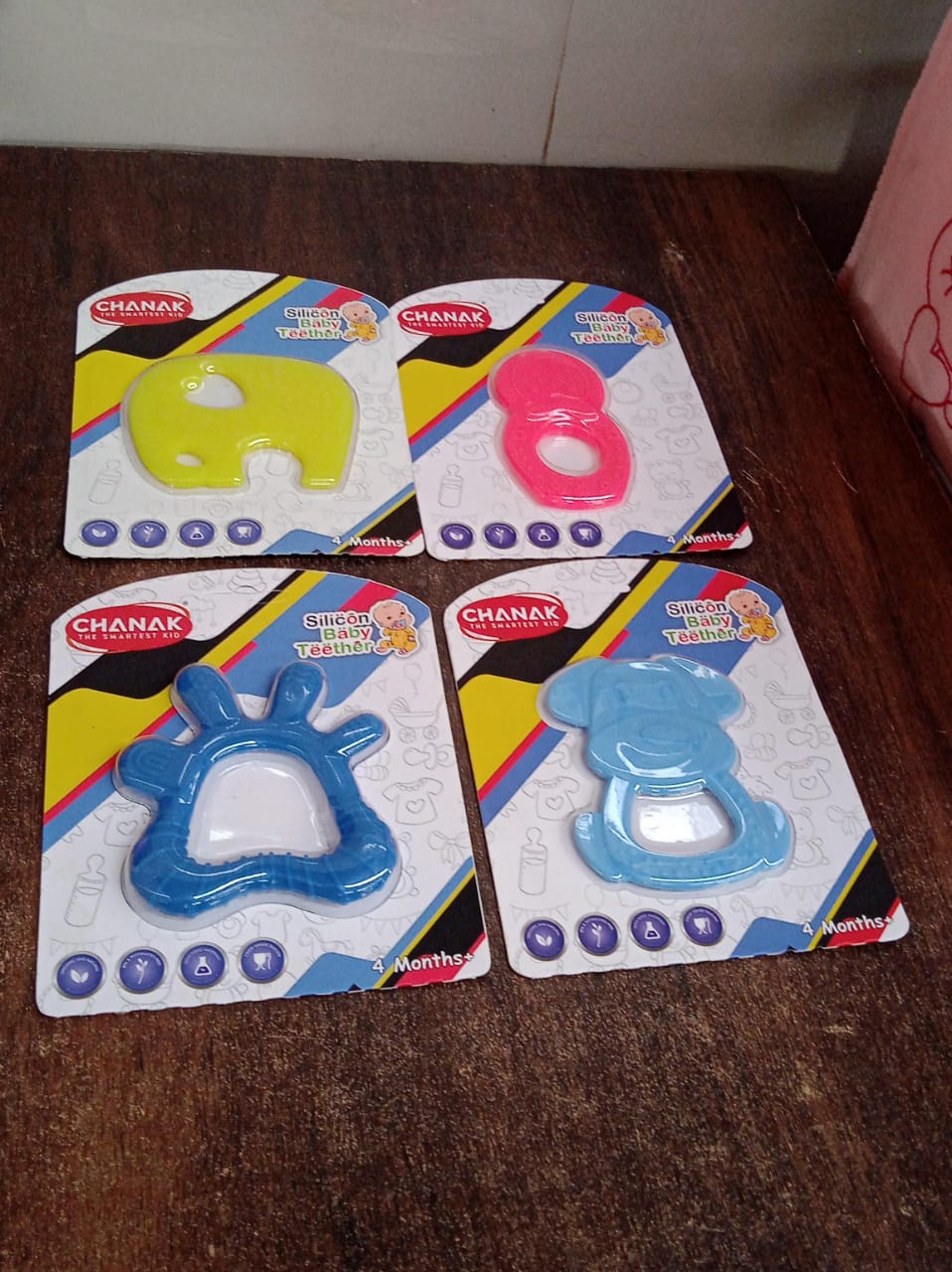 A happy baby smiling while holding a silicone teether, experiencing comfort.