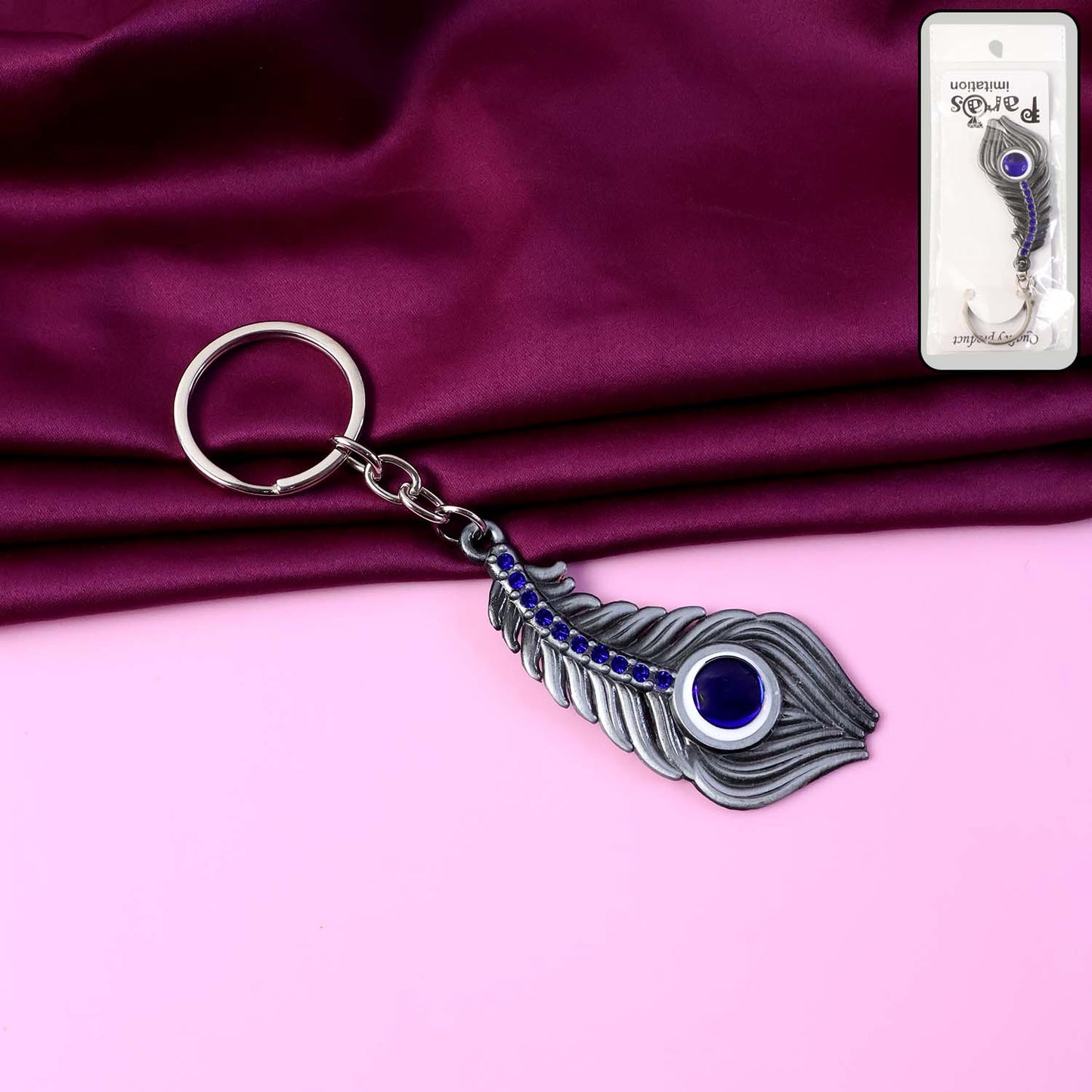 Elegant metal peacock feather keychain featuring blue gem accent