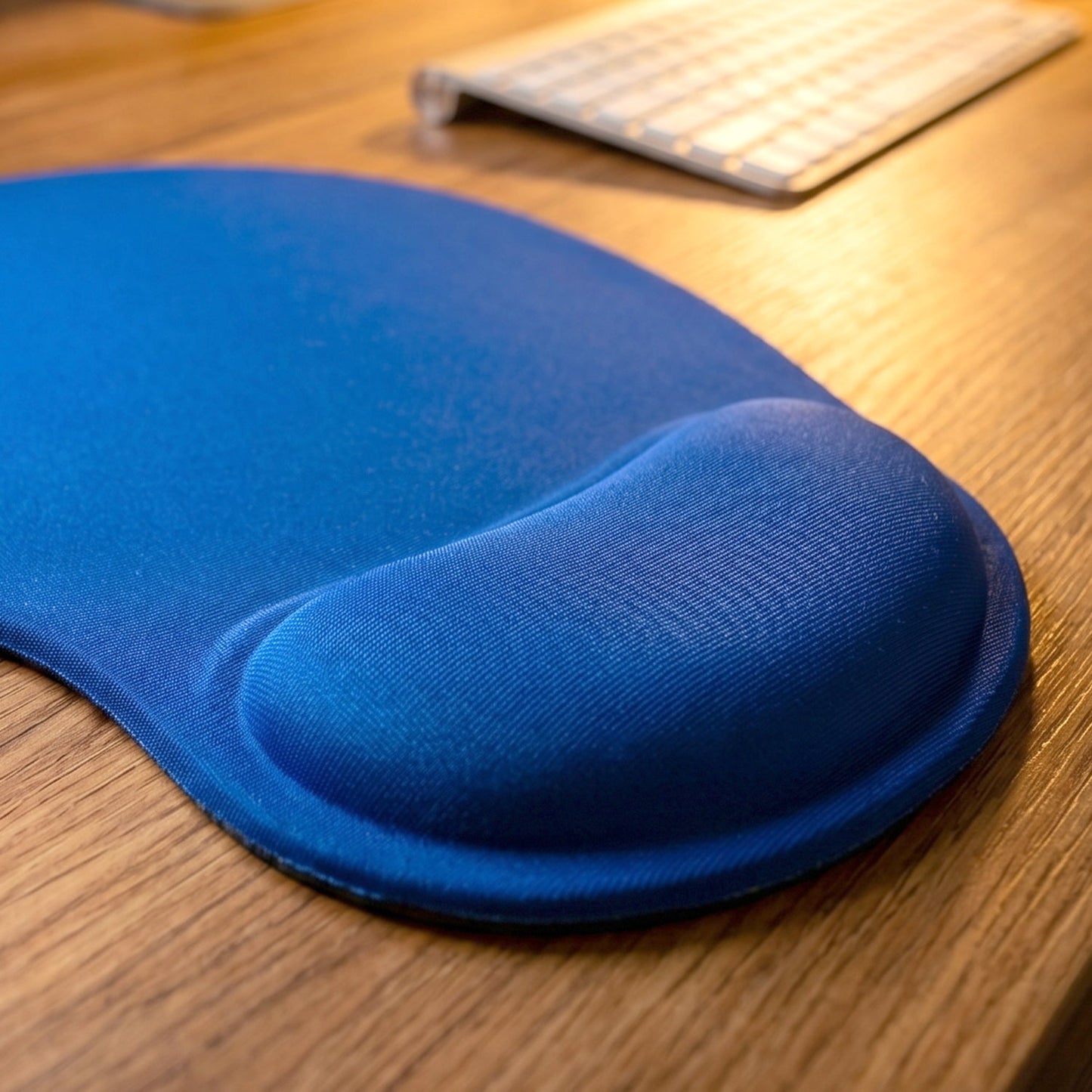 Ergonomic wrist rest mouse pad in use with a computer mouse, providing wrist support.