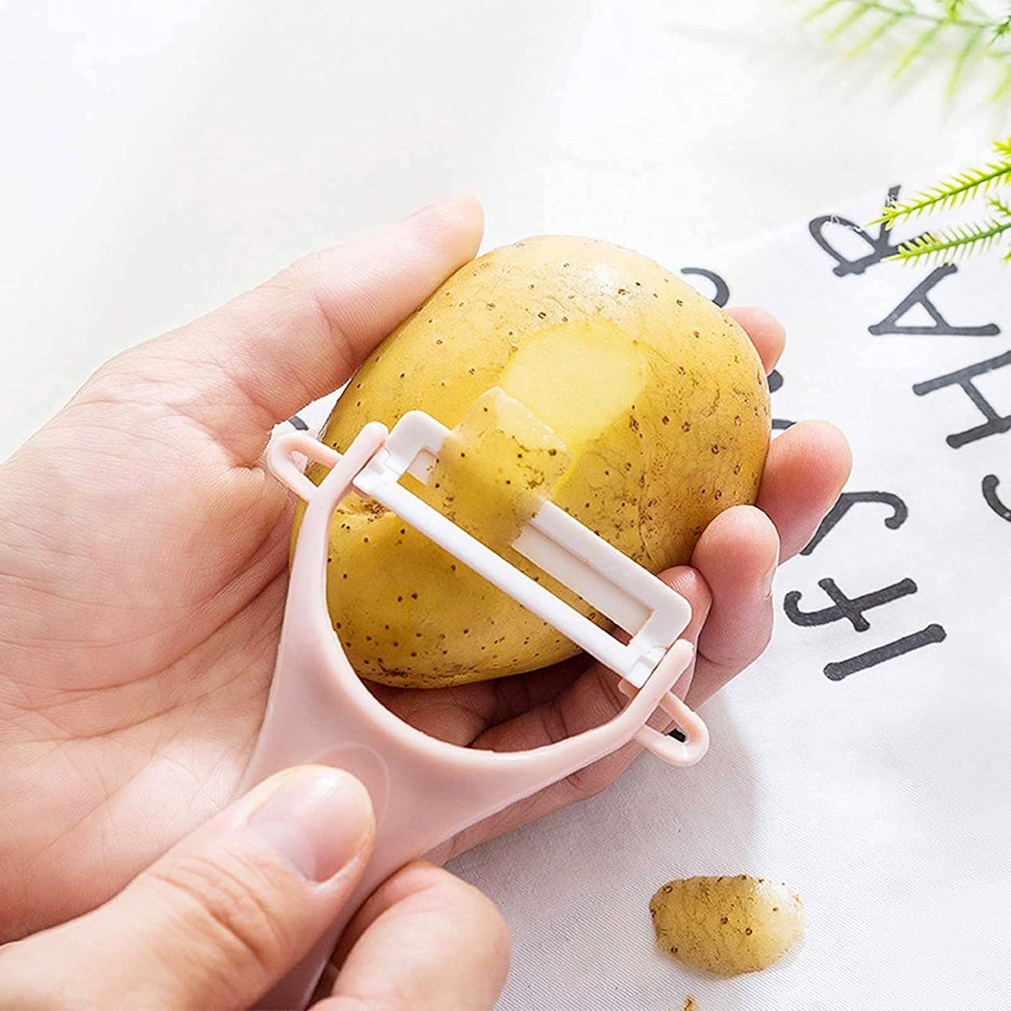 Hand holding the anti-slip handle of the Y-shaped fruit and vegetable peeler.