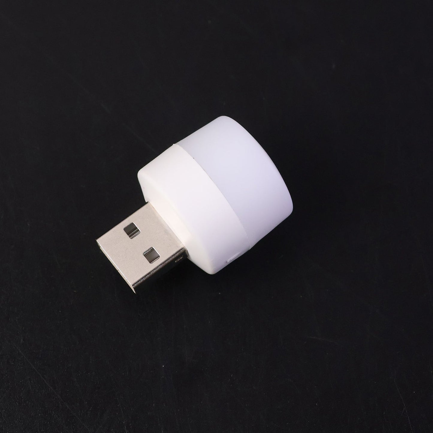 Mini portable yellow USB LED night light glowing beside a laptop keyboard